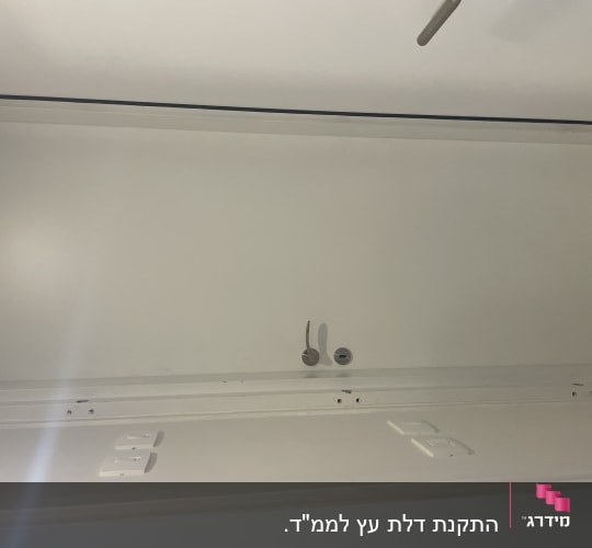 דלת לבנה עם ידית מתכת ומנעול עגול